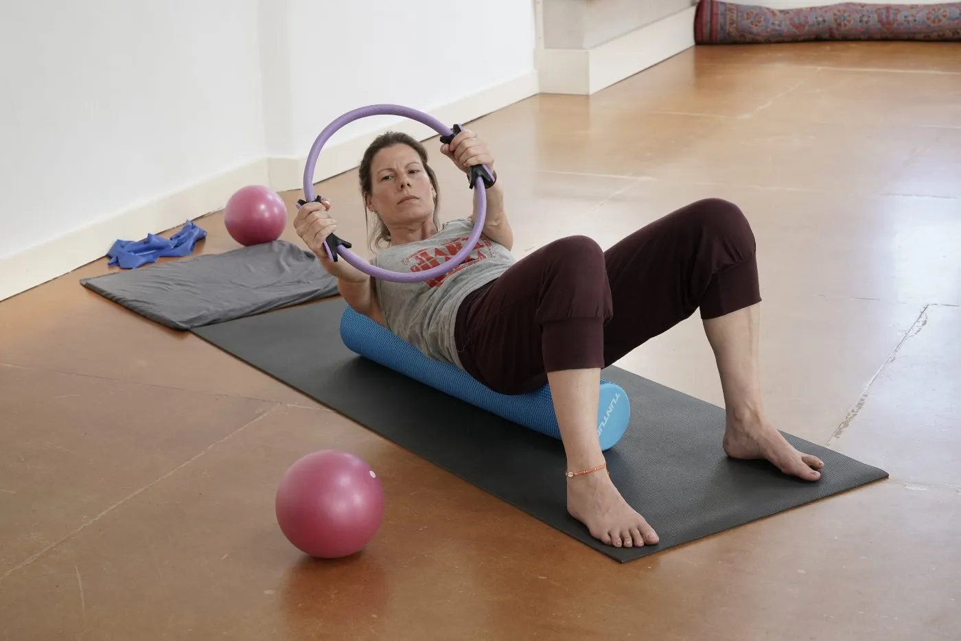 Cursist doet een pilatesoefening op de mat met een pilatesring